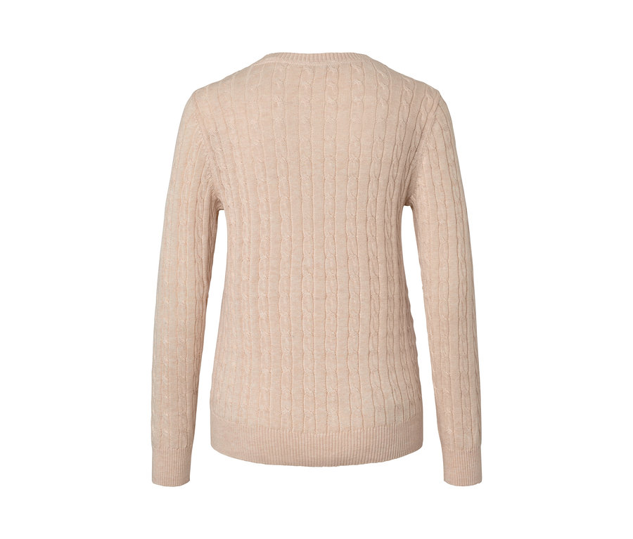 Detail krémového svetru s copánkovým vzorem.