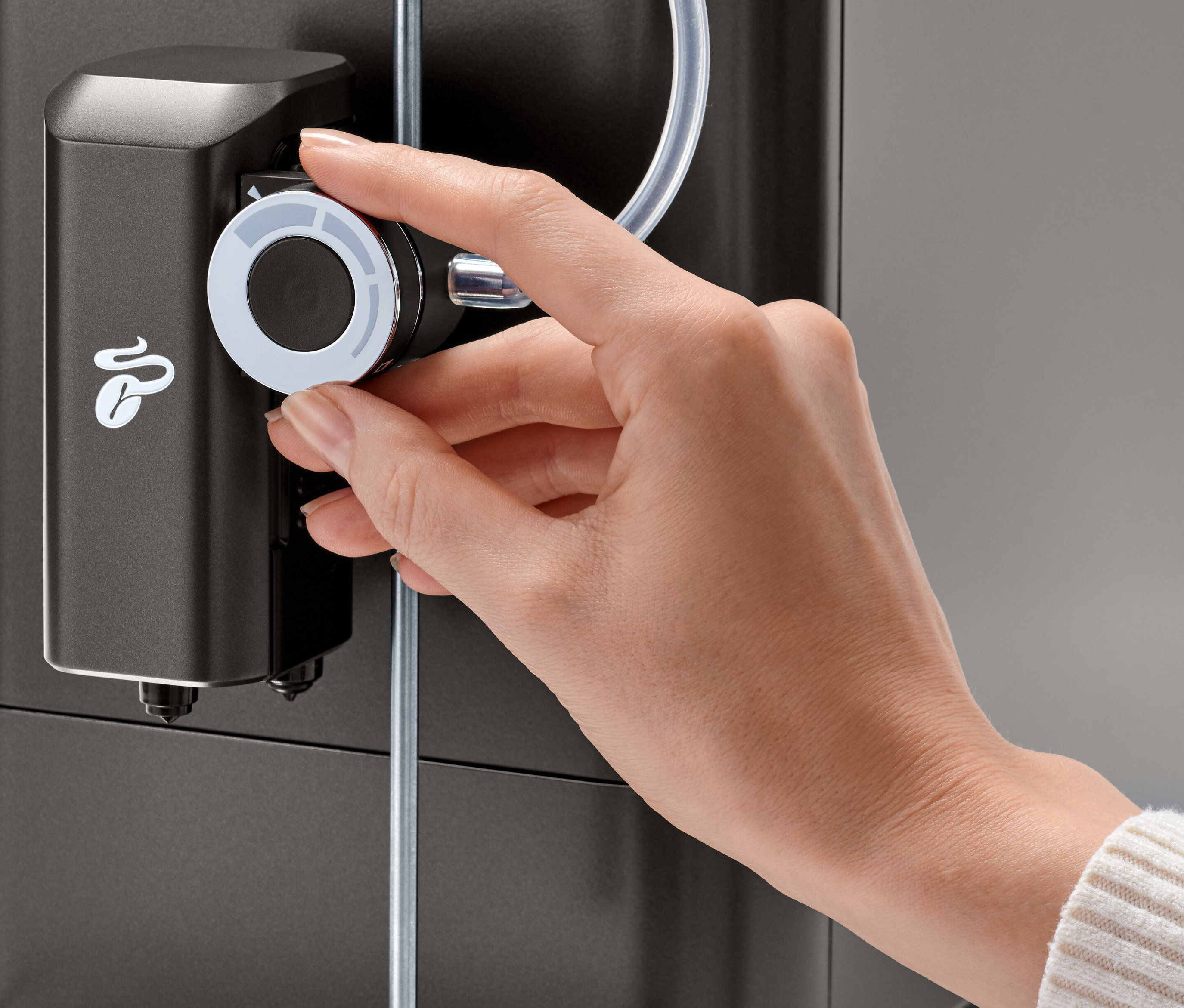 Ruka otáčí otočným regulátorem mléčné pěny na kávovaru Tchibo »Esperto 2 Milk« Granite Black.