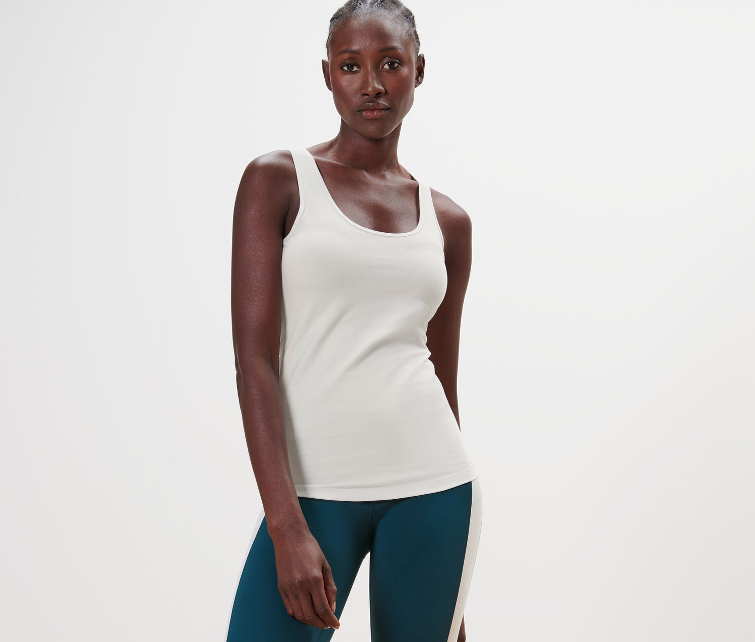 Černoška ve stoje má na sobě krémový top a zelené legíny.