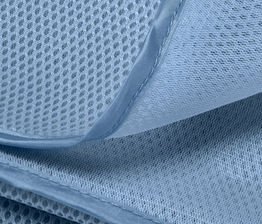 Detailní záběr plážové deky nepropouštějící písek, která ukazuje texturu a prodyšnost materiálu.