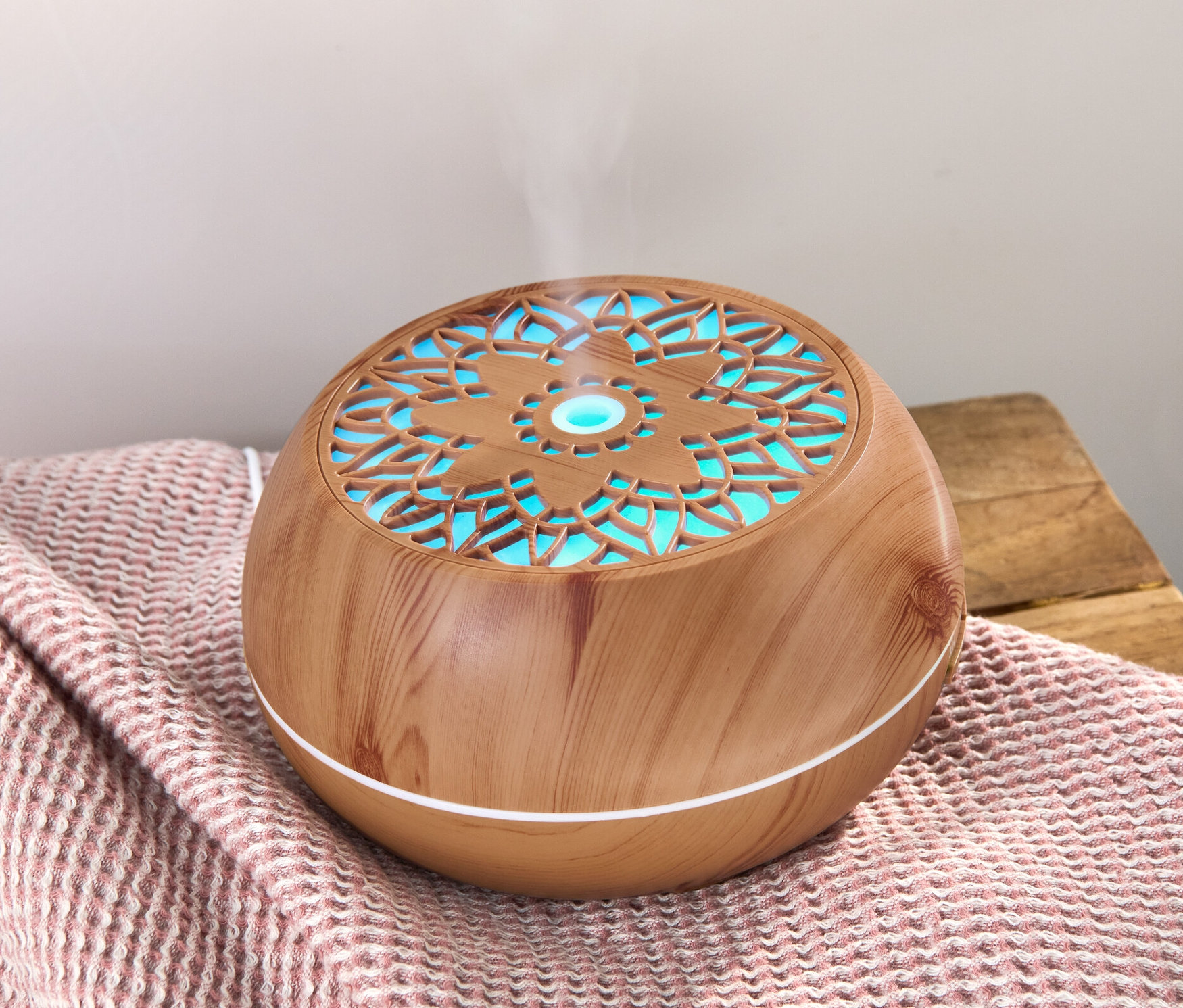 Aroma difuzér s reproduktorem Bluetooth® na ružové deke, z kterého stoupá pára.