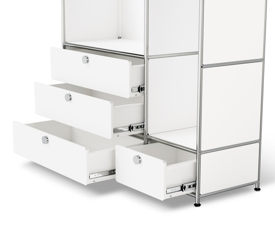 Detail bílé kovové skříně »CN3« se dvěma šatními tyčemi a čtyřmi zásuvkami, některé zásuvky jsou otevřené.