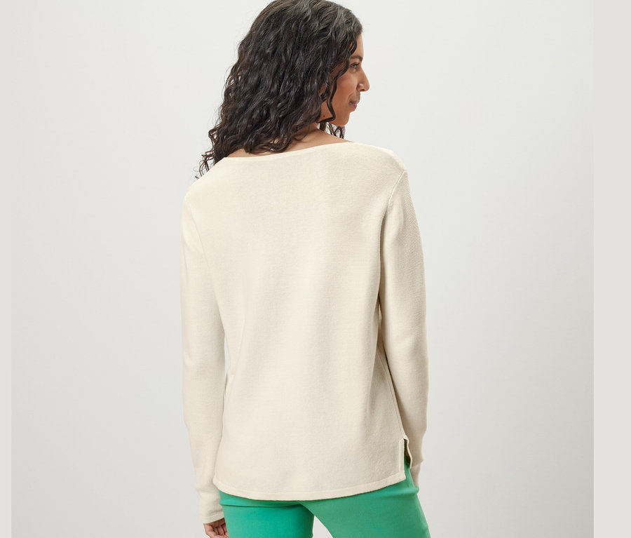 Žena zezadu nosí krémově bílý pletený svetr.