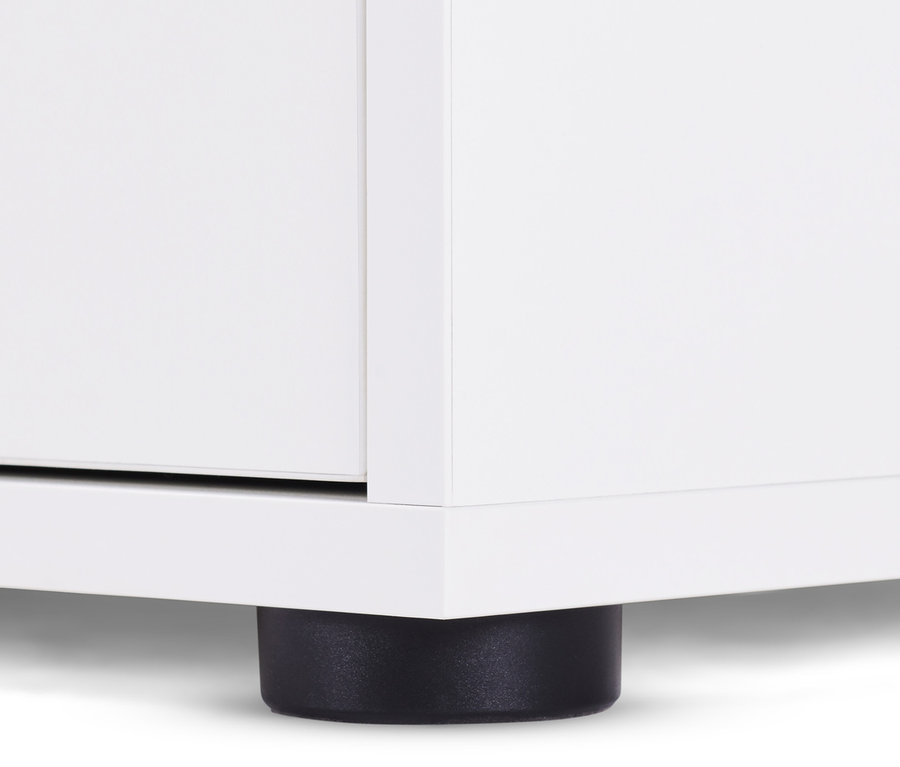 Detail bílé komody se zásuvkami a dvířky, s černou nohou.