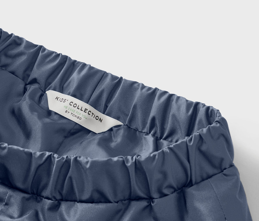 Detail modrých dětských kalhot s elastickým pasem a štítkem s nápisem Kids' Collection.
