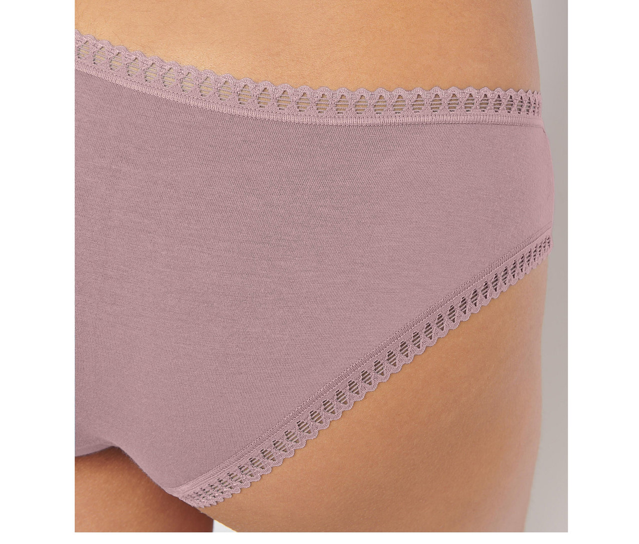 Detail osoby v světle růžových kalhotkách sloggi GO Crush Hipster s vlnkovaným krajkovým lemem v pase a na nohavičkách.