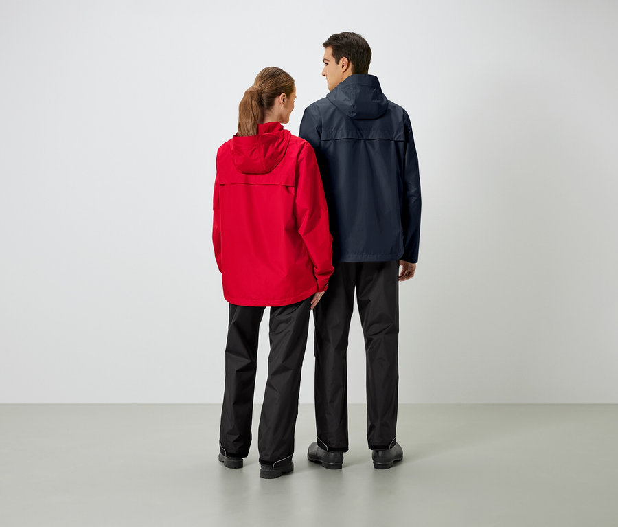 Dva lidé stojí zády ke kameře a mají na sobě bundy do deště a kalhoty do deště.