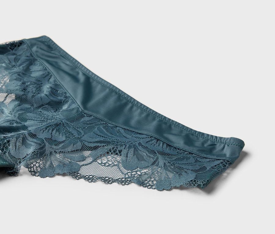 Detailní záběr modrých krajkových kalhotek.