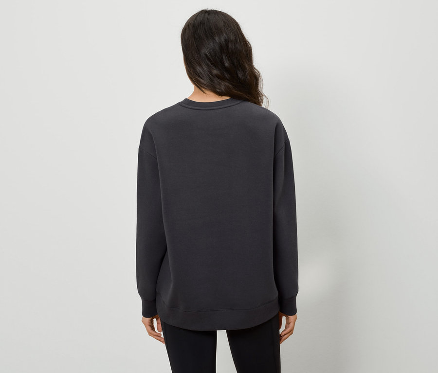 Zezadu je vidět žena v černém svetru a černých kalhotách.