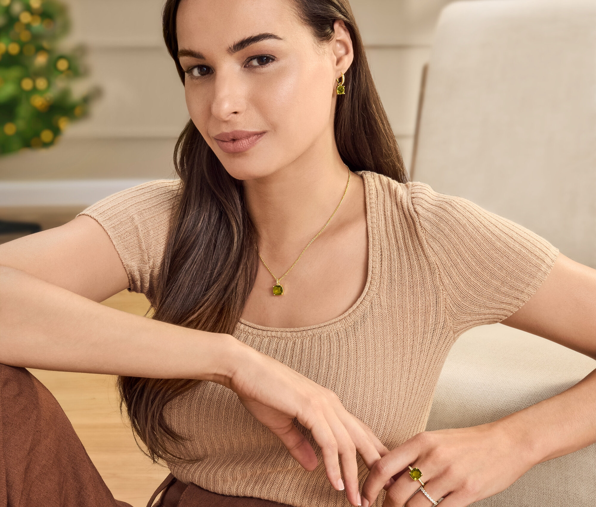 Žena sedí s náhrdelníkem, kruhovými náušnicemi a prstenem se zelenohnědým skleněným kamínkem.