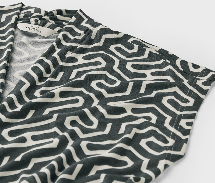 Detail zeleného halenkového trika s výstřihem do V se vzorem.