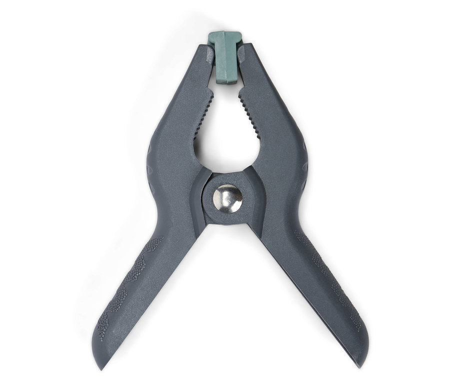 Detailní záběr na jednu šedou plastovou svěrku s zelenou špičkou na bílém pozadí.