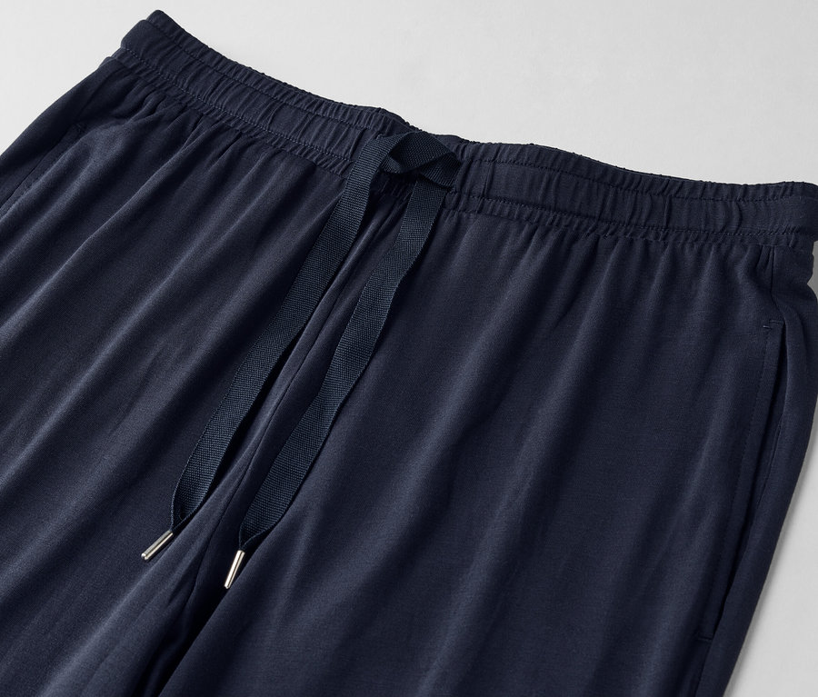 Detailní záběr na tmavě modré tepláky se stahovací šňůrkou.