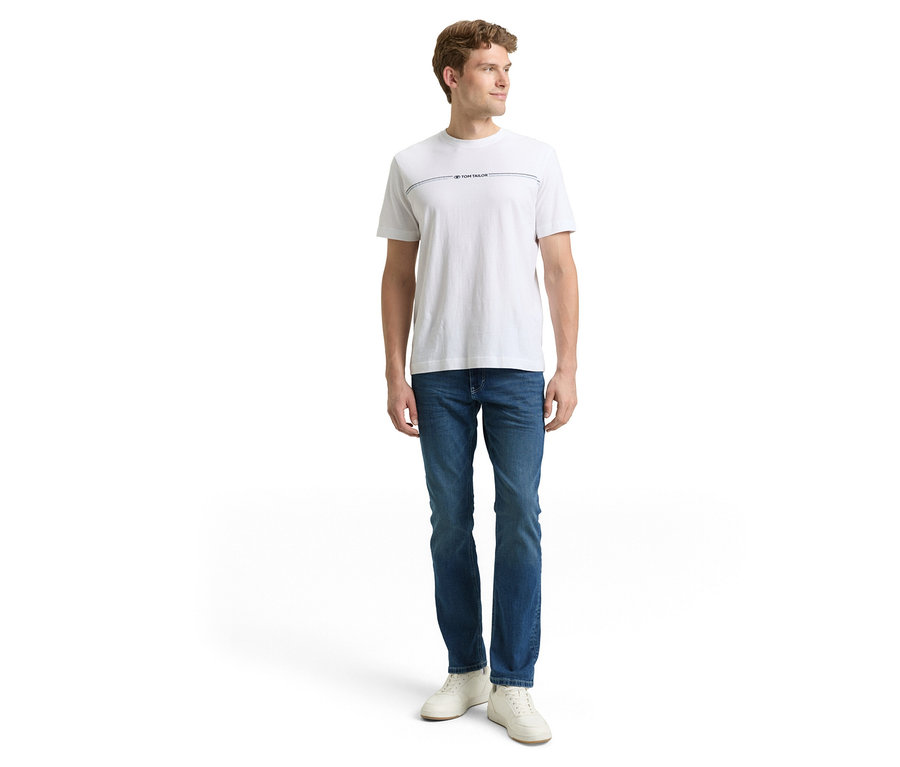 Muž v džínách a tričku. Má na sobě Džíny Tom Tailor TT MARVIN STRAIGHT se strečovým materiálem, Used Mid Stone Blue Denim.