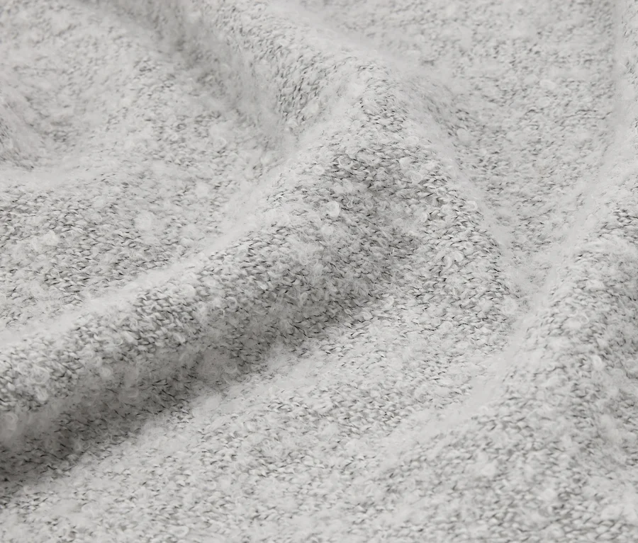 Detailní záběr pomačkané, světle šedé látky s nadýchanou texturou.