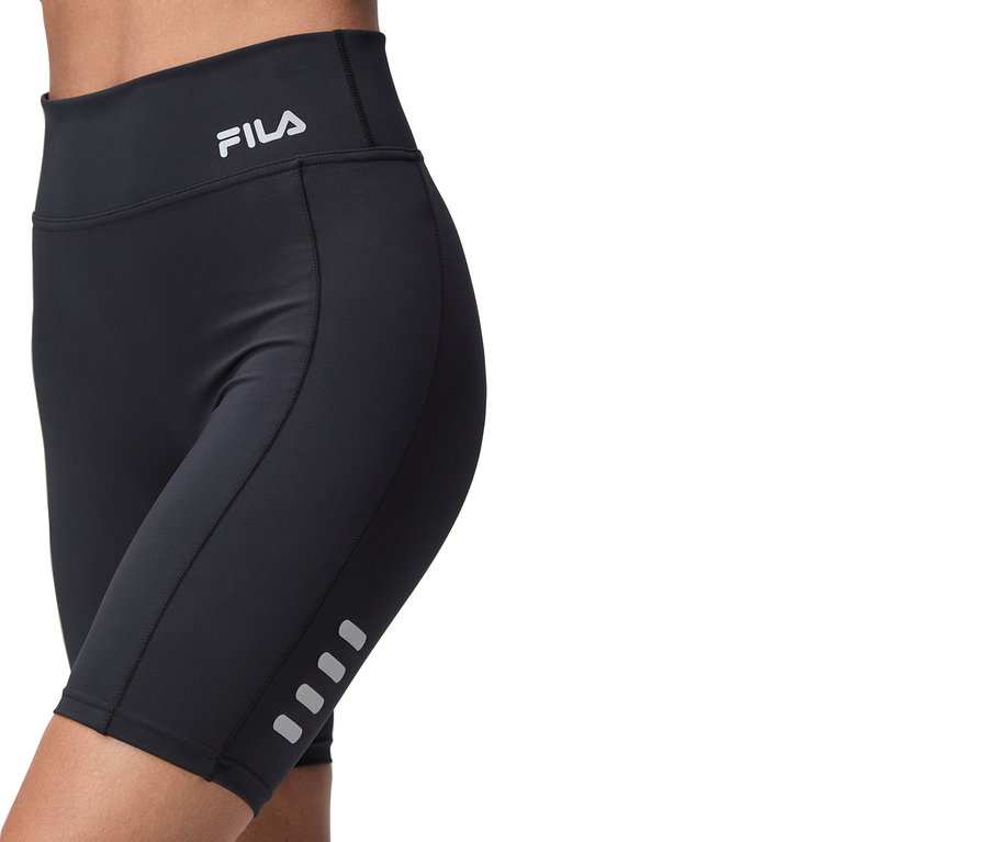 Detailní záběr na osobu v černých cyklistických šortkách Fila s logem Fila na pasu a reflexními detaily na nohou.