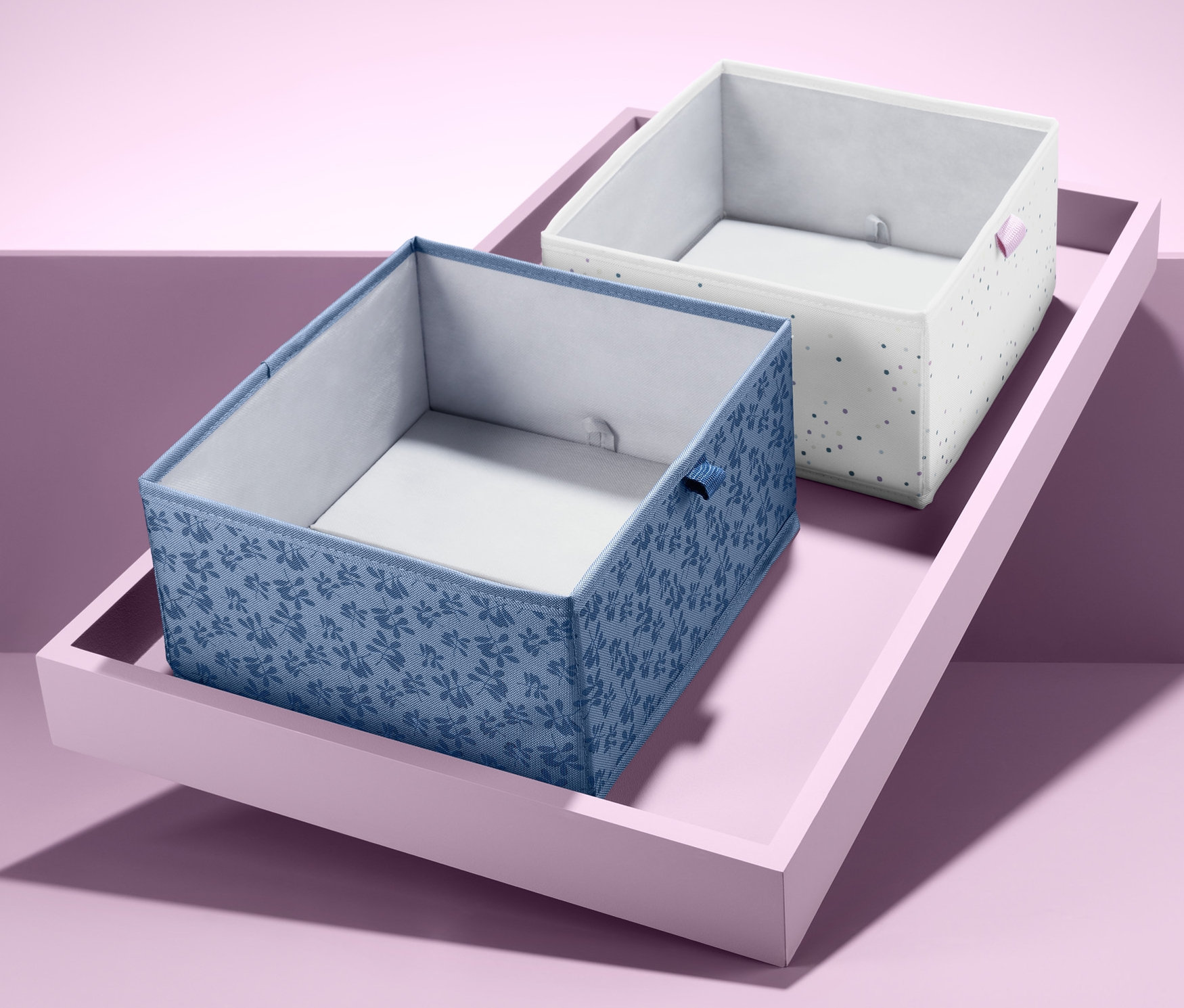 Dva čtvercové organizéry do zásuvky na růžovém podnosu.