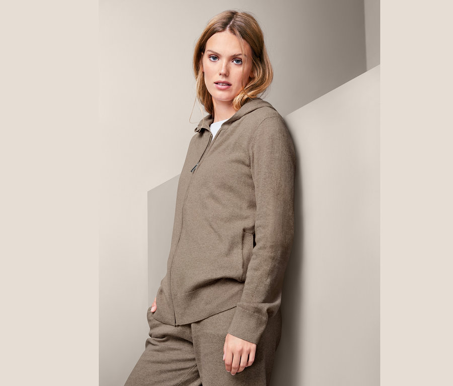 Žena pózuje v kašmírové mikině s kapucí.