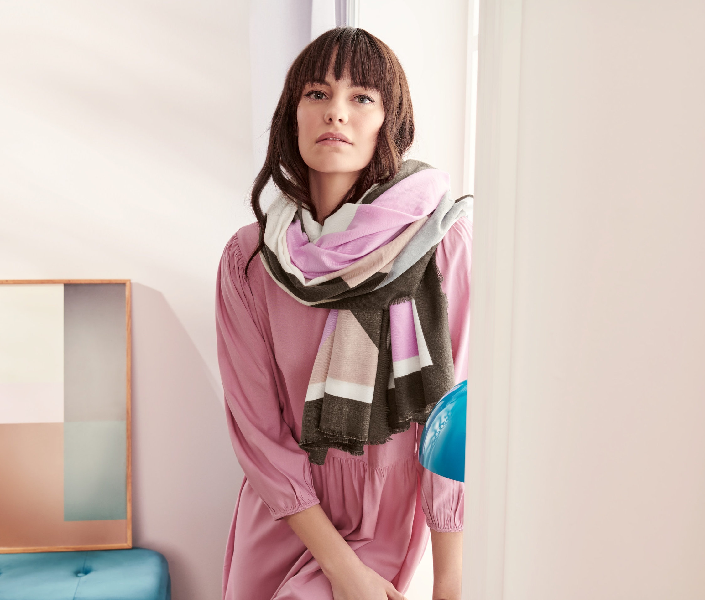 Žena v růžových šatech má na sobě šálu.