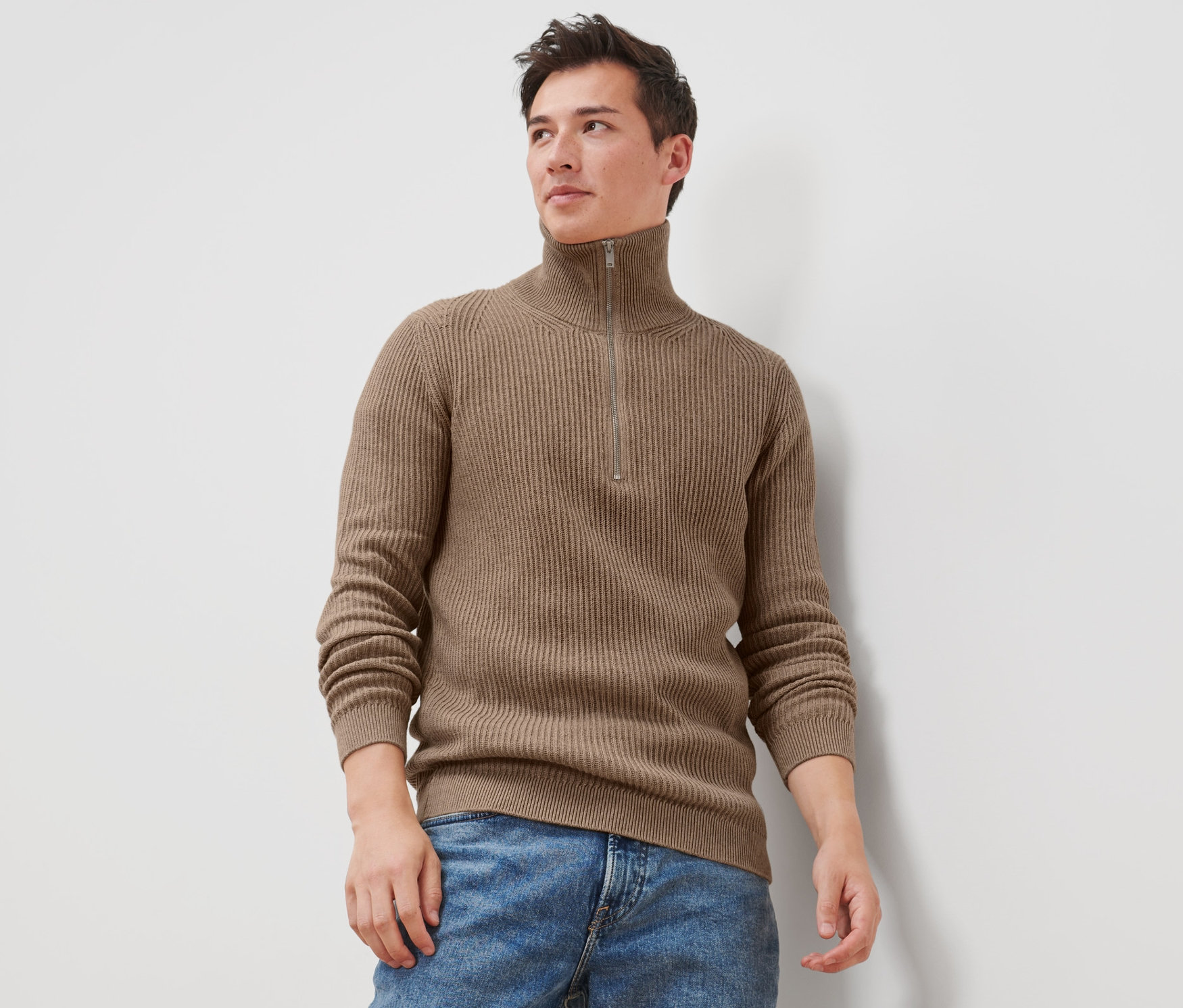 Muž má na sobě svetr troyer a džíny.