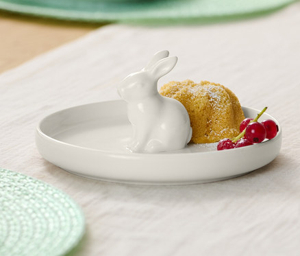 Talíř s velikonočním zajíčkem, bábovka a červený rybíz na stole.