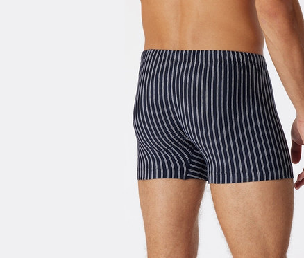 Muž zezadu má na sobě tmavě modré trenýrky SCHIESSER s biobavlnou s bílými proužky.