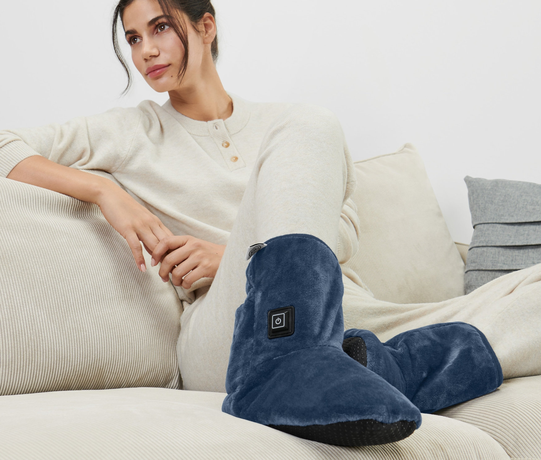 Žena sedí na gauči a má na sobě vyhřívané boty.