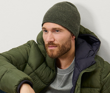 Muž sedí a má na sobě khaki melírovanou pletenou čepici.
