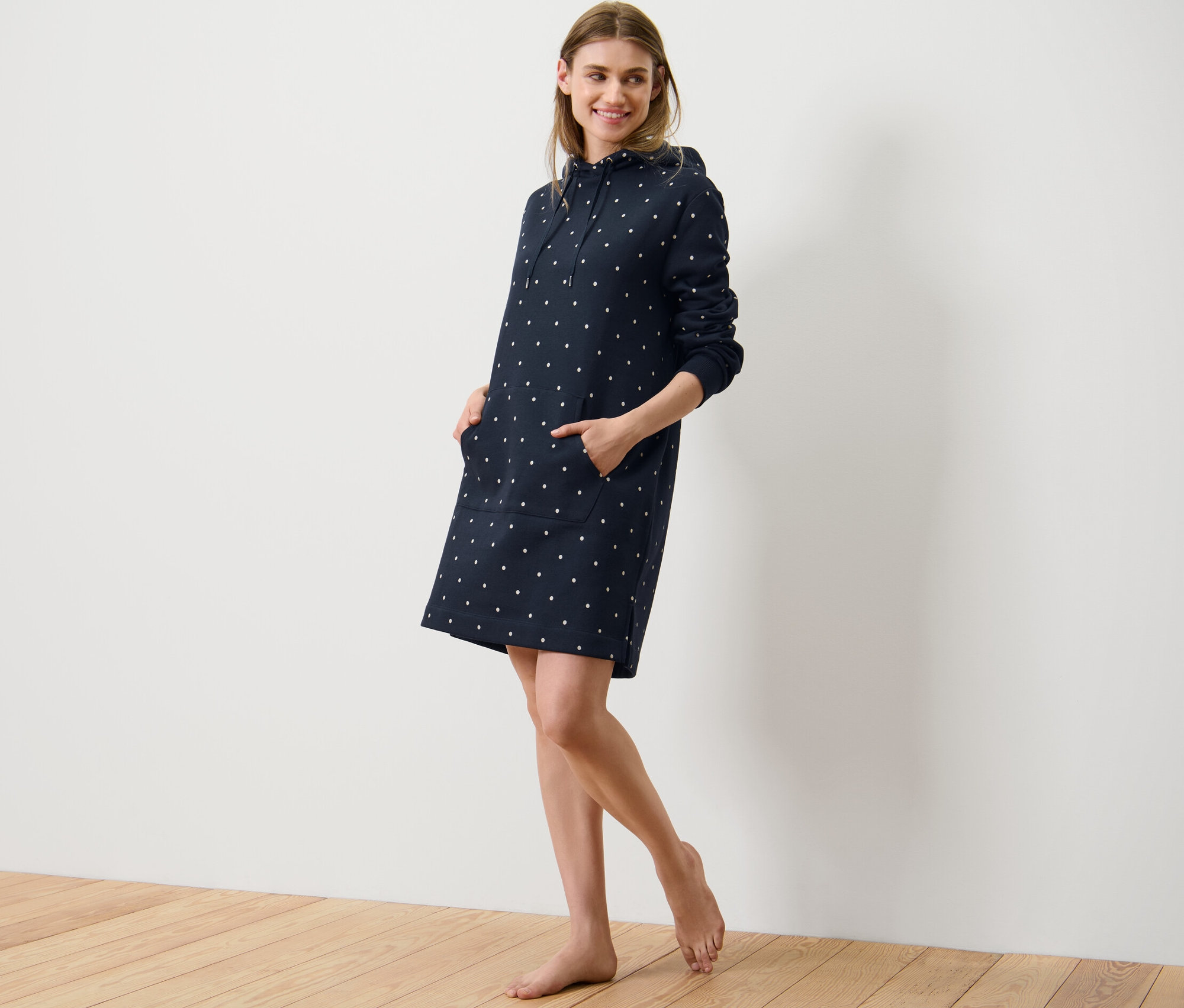 Žena pózuje v pohodlných šatech s puntíky.