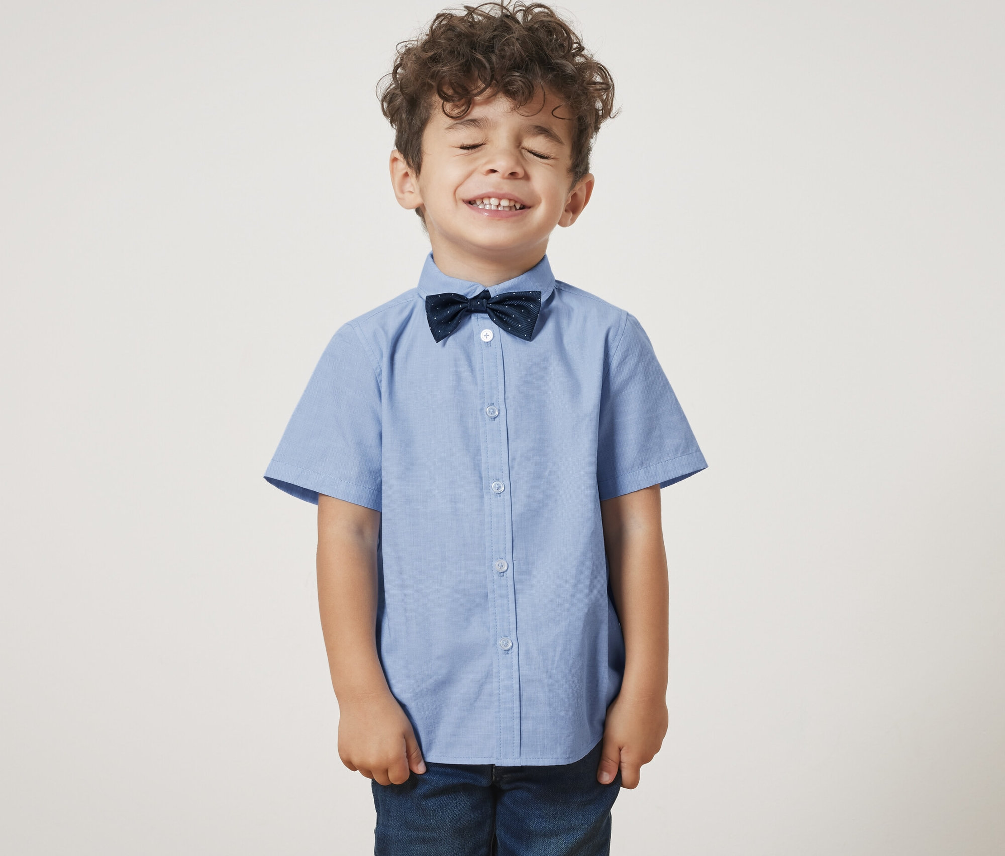 Chlapec se zavřenýma očima má na sobě chlapeckou košili s motýlkem.