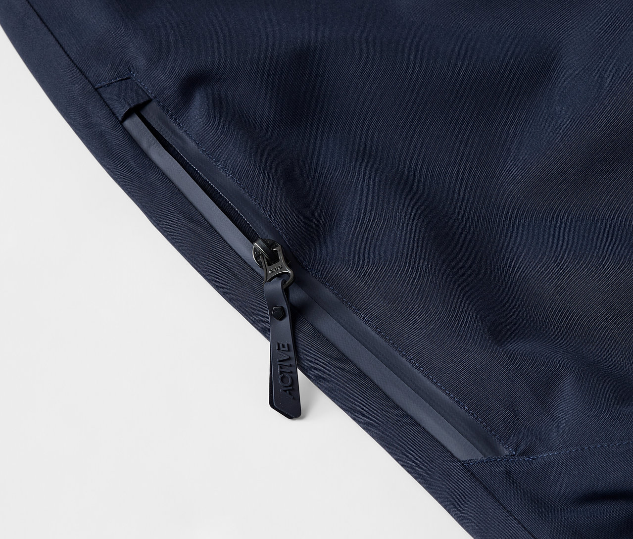 Detail tmavě modré bundy se zipem a logem.