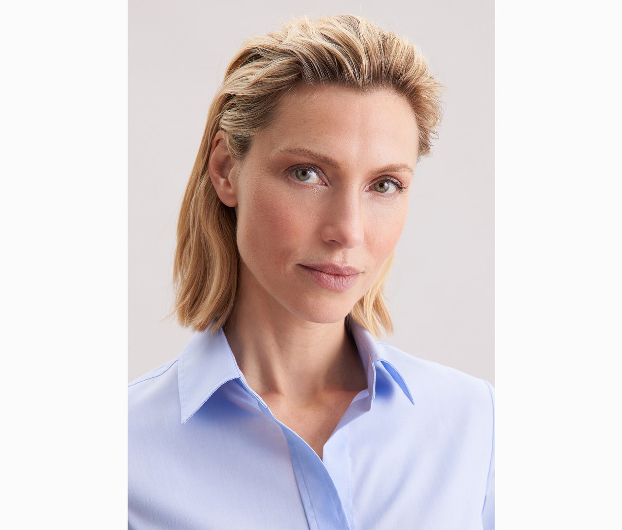 Žena má na sobě světle modrou halenku Seidensticker Slim Fit non iron.