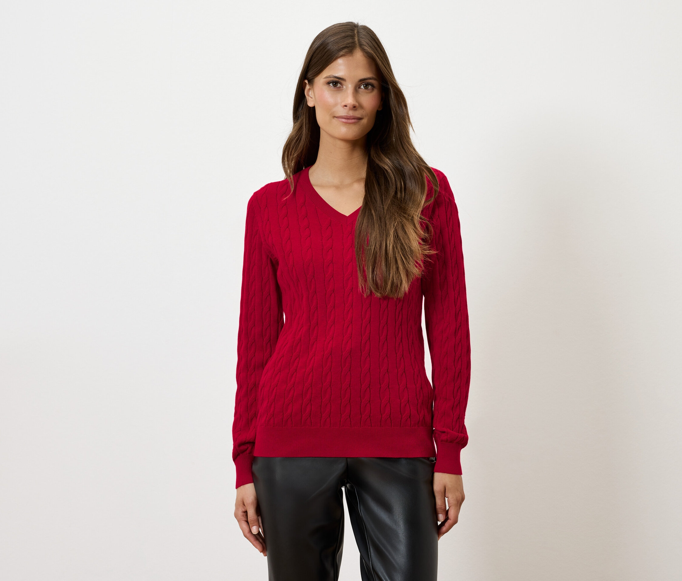 Žena má na sobě červený svetr a černé kalhoty.