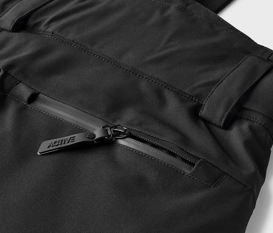 Detail černých kalhot s kapsou na zip s jezdcem s nápisem ACTIVE.