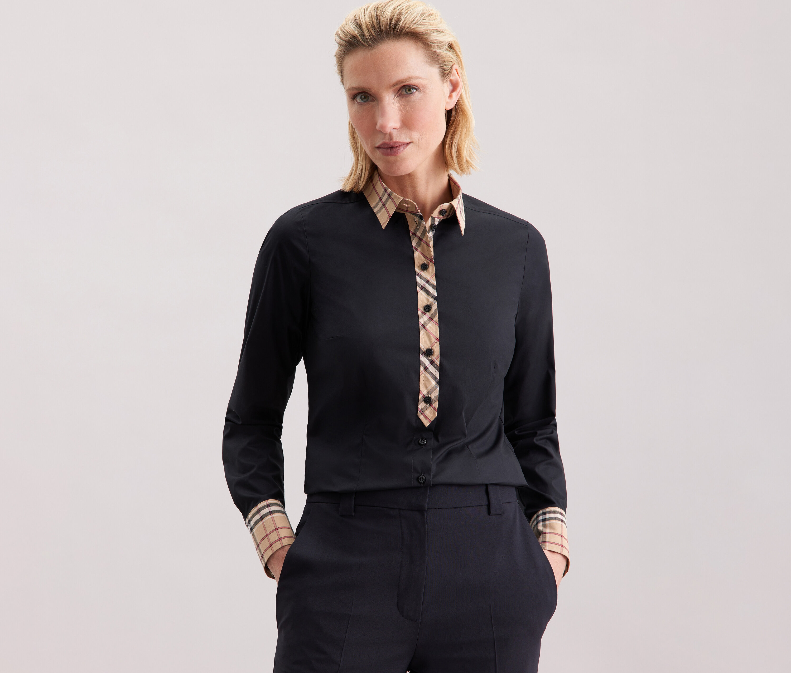 Žena má na sobě popelínovou halenku Seidensticker s kostkovaným detailem.