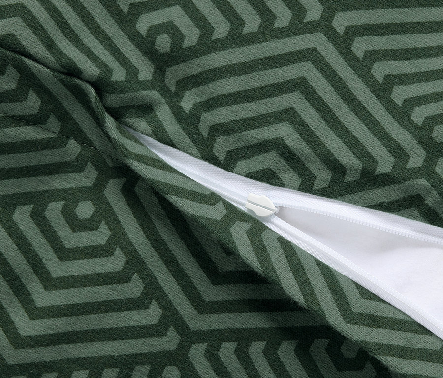 Detailní záběr na dva zelené povlaky na polštáře z biberu s geometrickým vzorem a zipem.