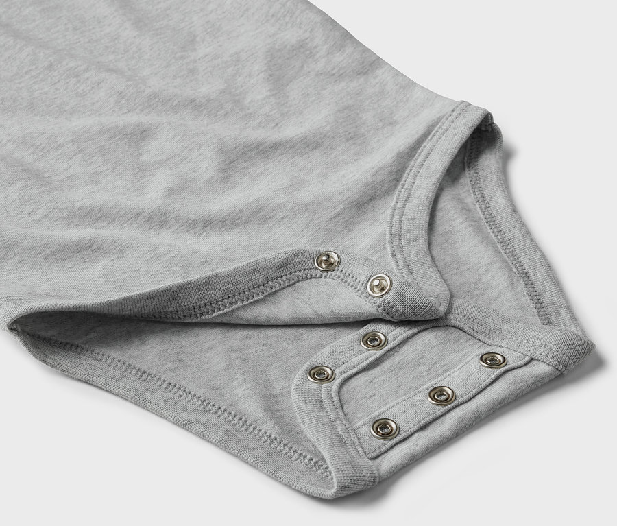 Detail šedého rostoucího body pro miminka s patentkami.