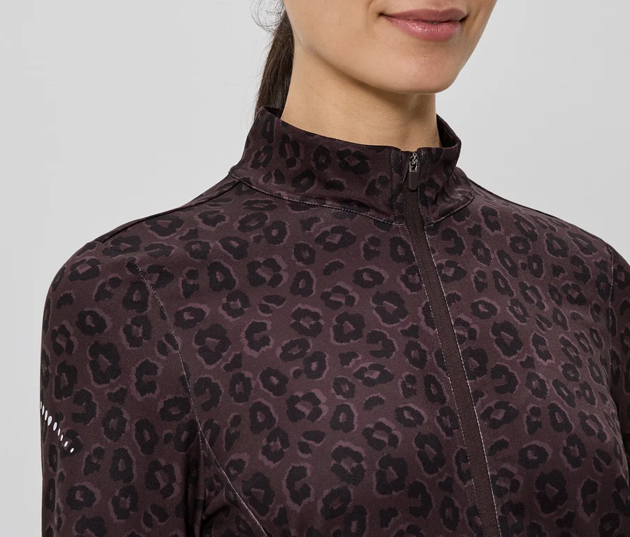 Detailní záběr ženy v hnědé tréninkové bundě se zipem a leopardím vzorem.