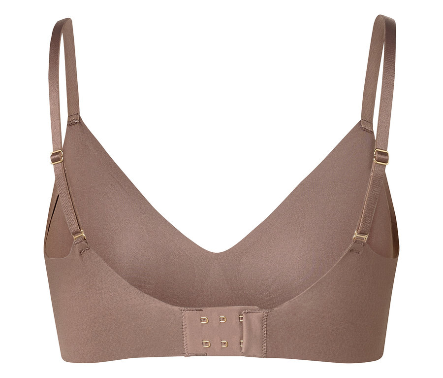 Detailní záběr béžové podprsenky s nastavitelnými ramínky a háčkovým zapínáním vzadu.