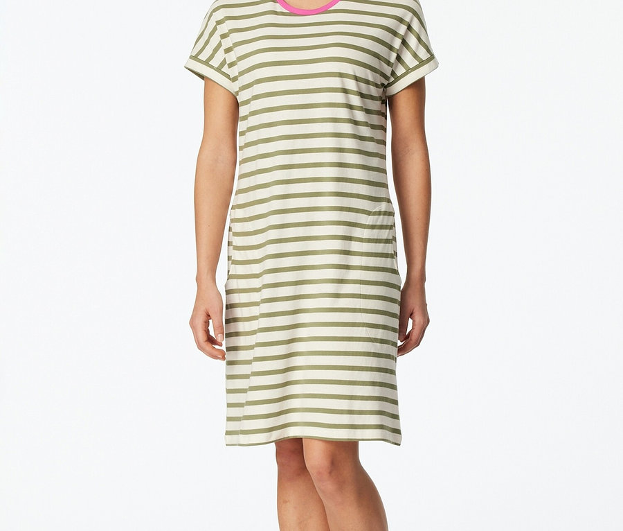 Žena stojí bosá a má na sobě pruhované tričkové šaty s růžovými akcenty na krku.