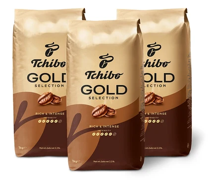 Tři balení kávy Tchibo Gold Selection stojí na bílém pozadí.
