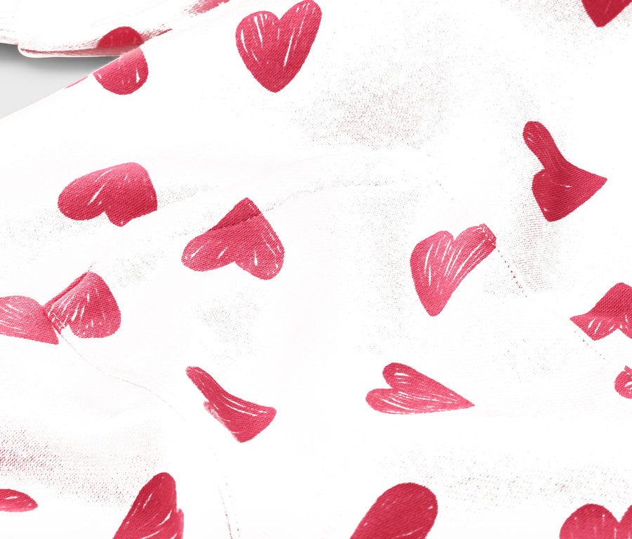 Detail bílé látky s červeným vzorem srdce.