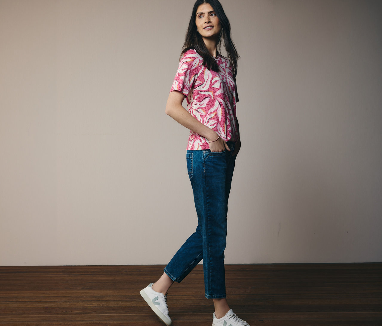 Žena jde v růžovém tričku s krátkým rukávem CECIL a džínách. Ruce má v kapsách.