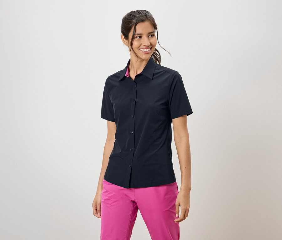 Žena má na sobě tmavě modrou košili s krátkým rukávem a růžové kalhoty.