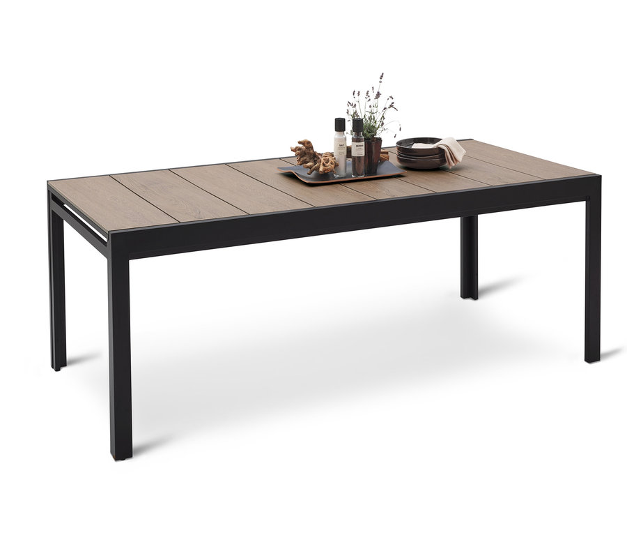 Jídelní stůl s dřevěnou deskou a černým kovovým rámem. Na stole jsou talíře, dekorativní předměty a rostliny.