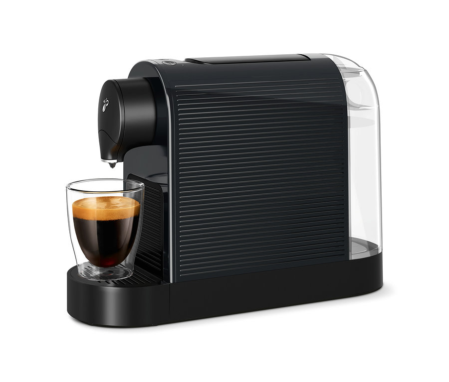 Káva teče do sklenice z černého kávovaru Cafissimo pure+.