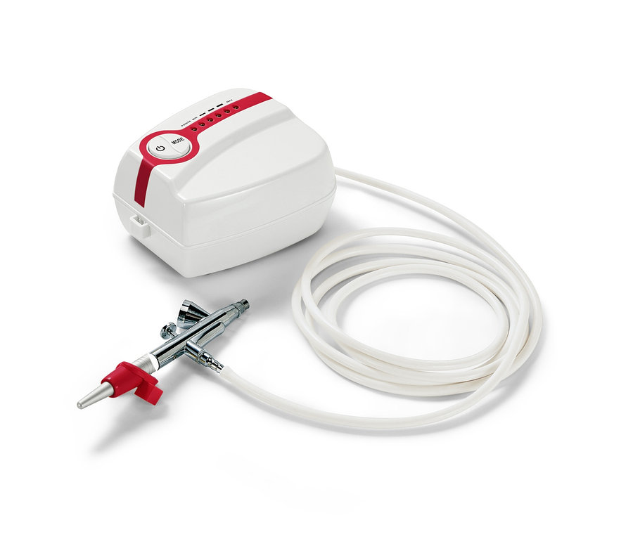 Sada airbrush na dorty a cukroví se stříkací pistolí a kompresorem na bílém pozadí.