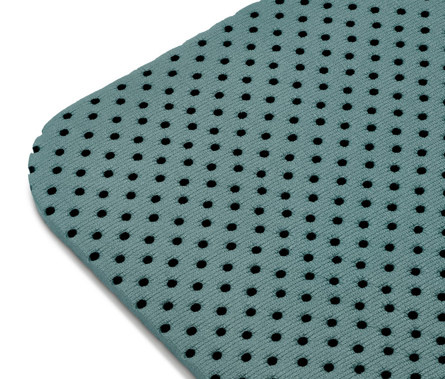 Detail zelené podložky na jógu a cvičení s černými otvory.