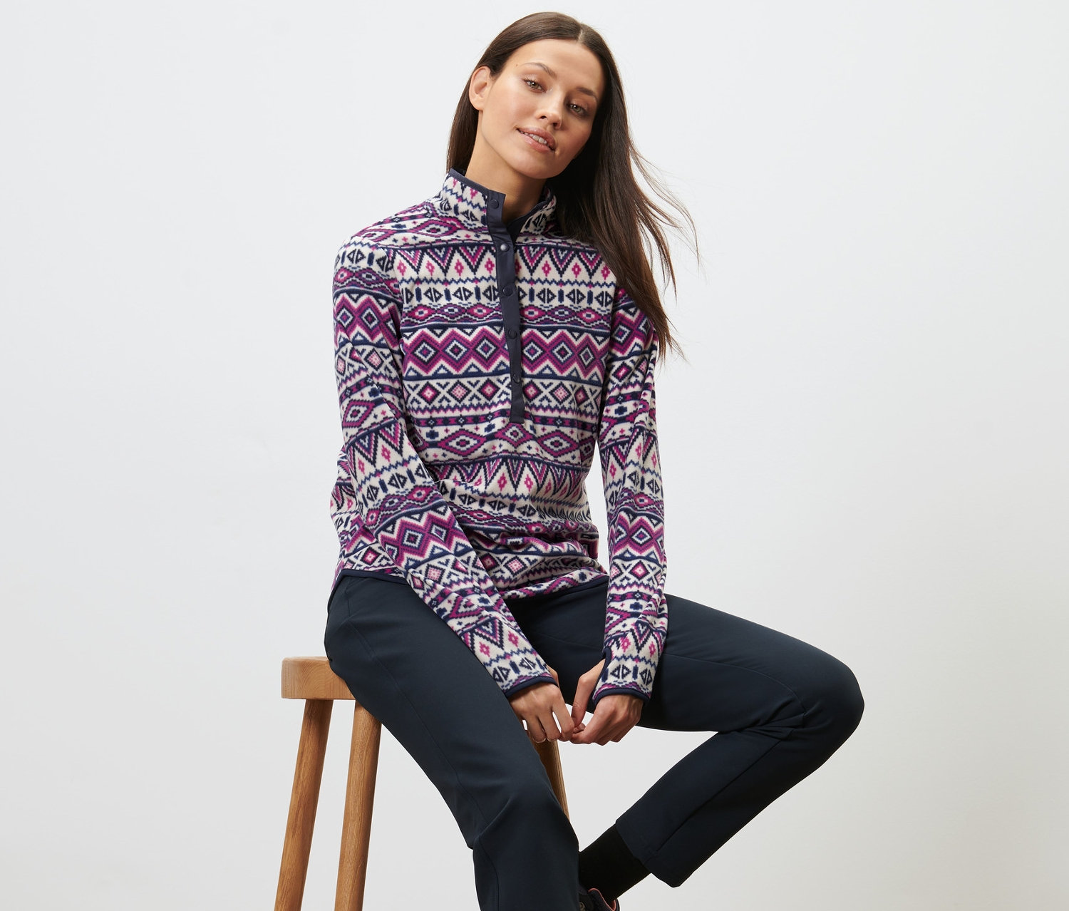 Žena sedí na stoličce a má na sobě fleecovou mikinu.