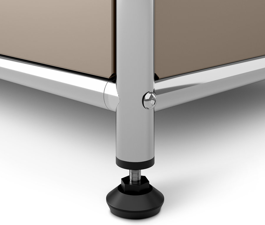 Detail šedobéžové kovové komody CN3 s výklopnými dvířky, chromovaná noha s černou patkou.